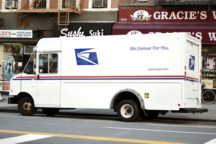 A USPS truck parked in front of storefronts